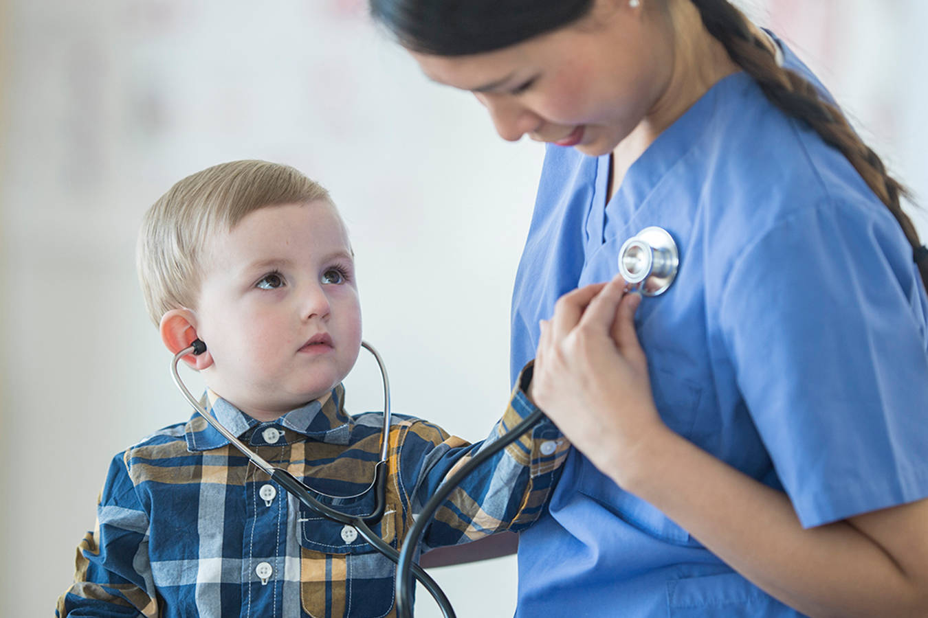 Young boy putting a stethiscope on the chest of a nurse