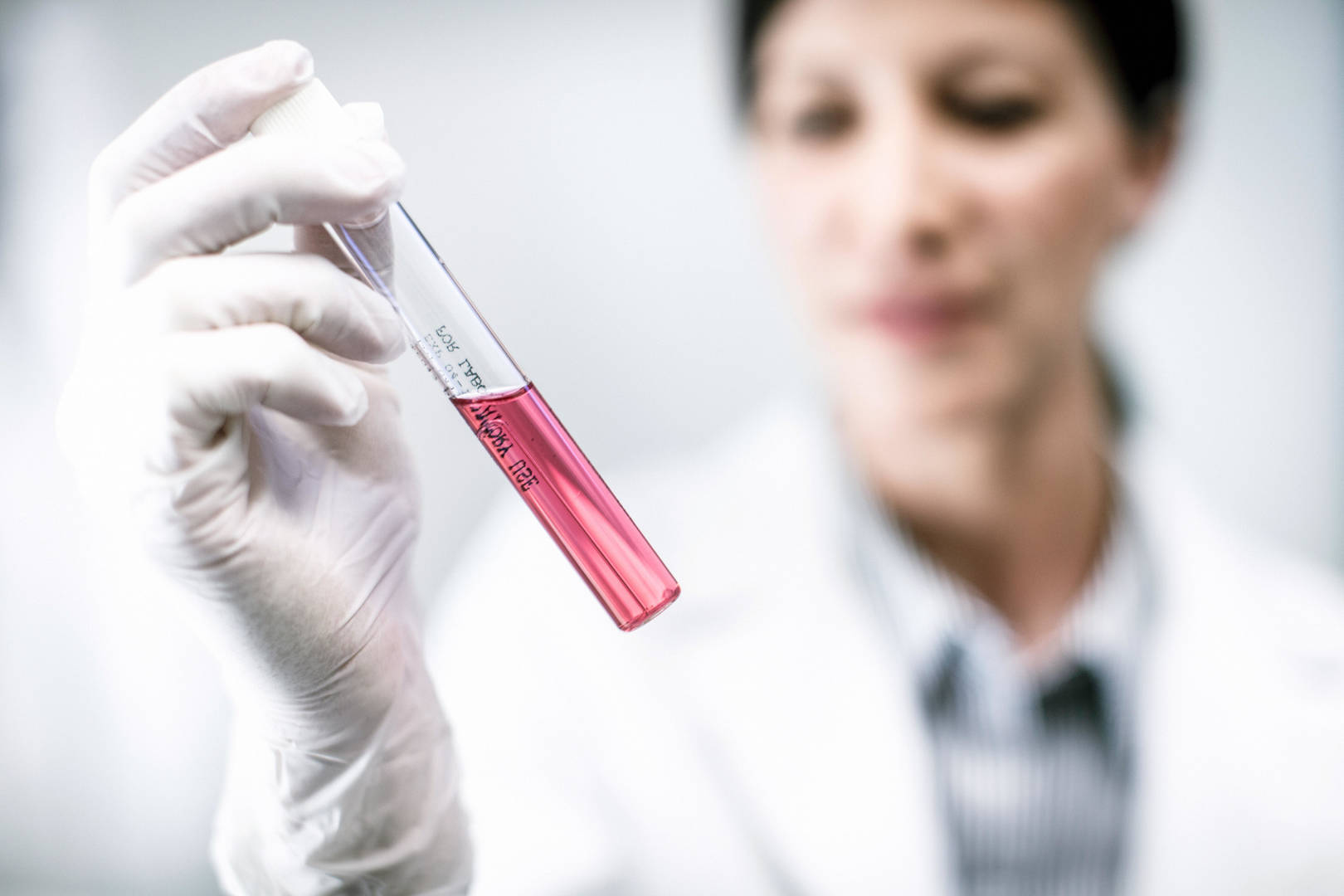 A female scientist examining the contents of a sample tube.